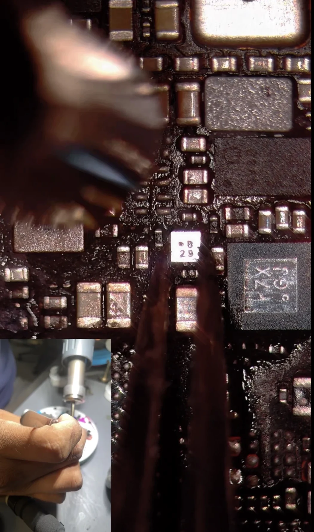 Tweezers placing the tiny baseband EEPROM chip onto an iPhone 14 Pro Max board under a microscope