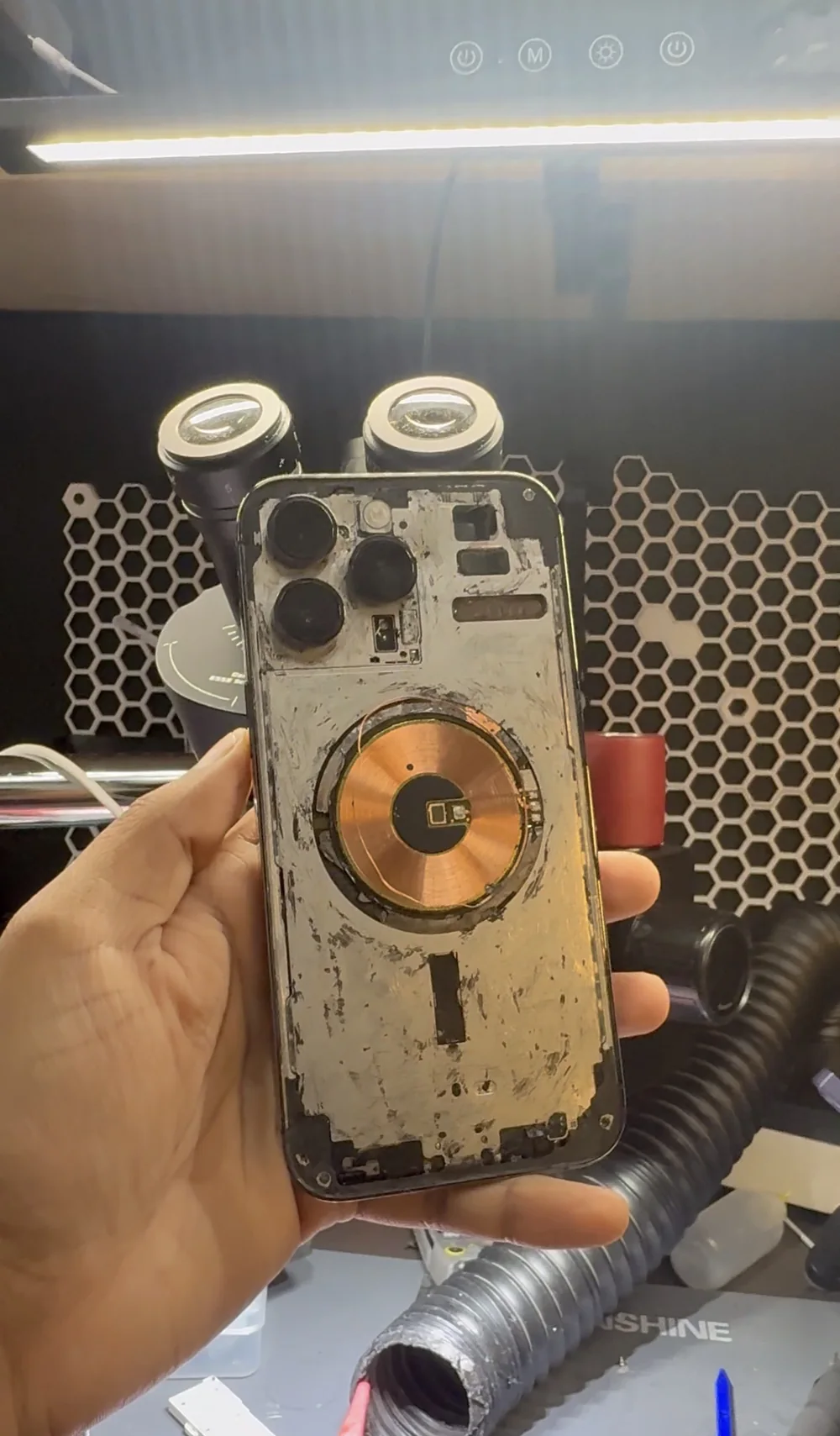 iPhone 14 Pro Max with the shattered back glass removed, exposing the MagSafe coil and internal frame
