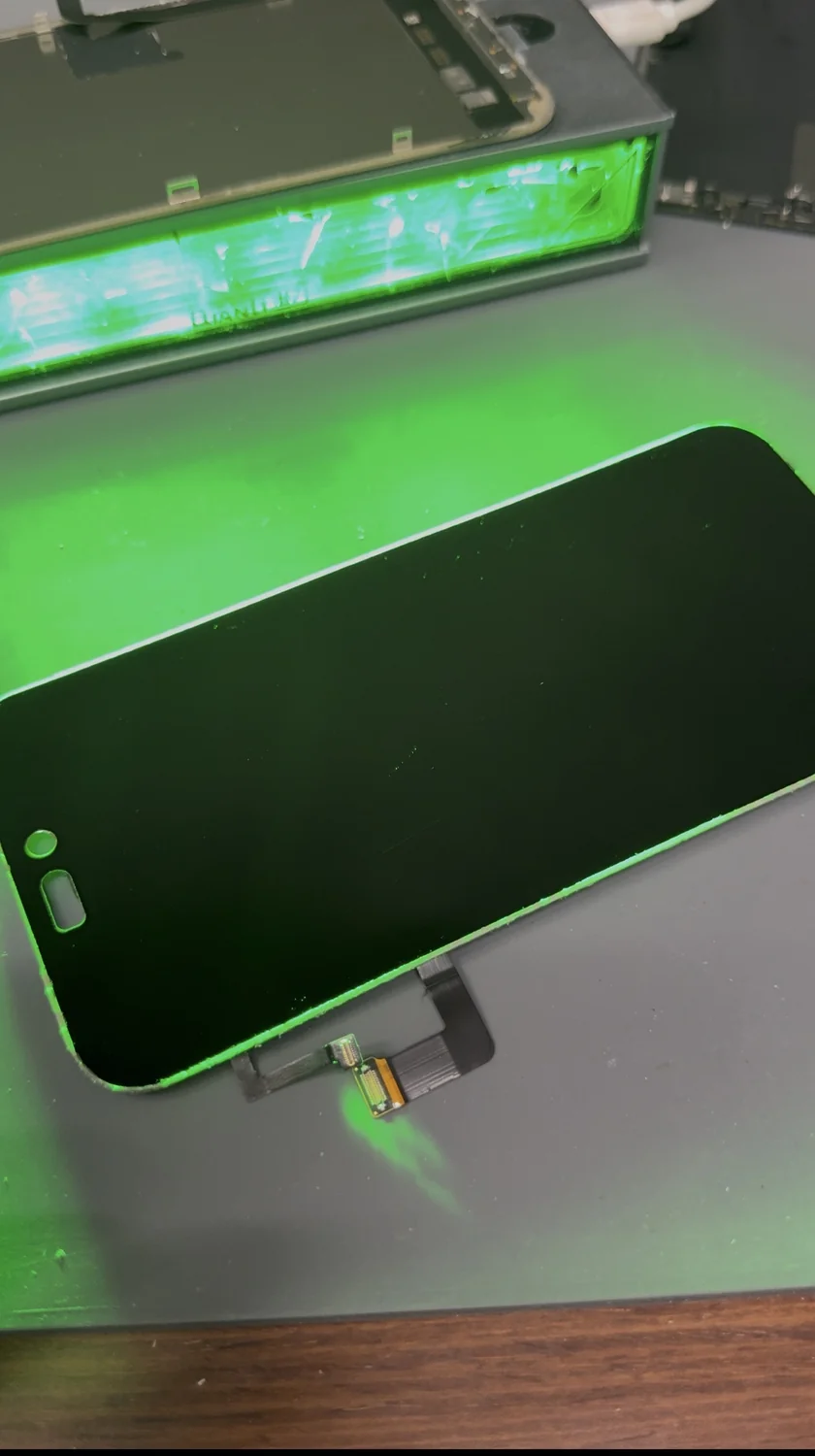 iPhone 17 Pro Max display checked under a green dust-inspection lamp before re-lamination