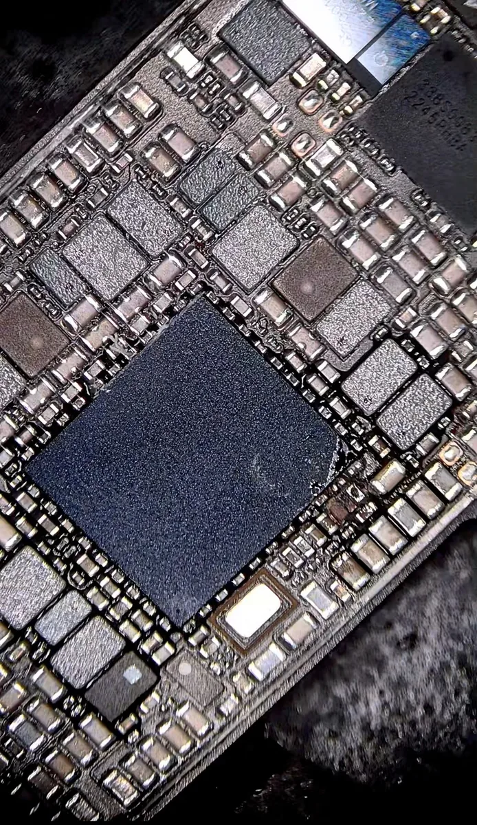 The power management IC mounted on an iPhone 14 logic board, surrounded by dense components