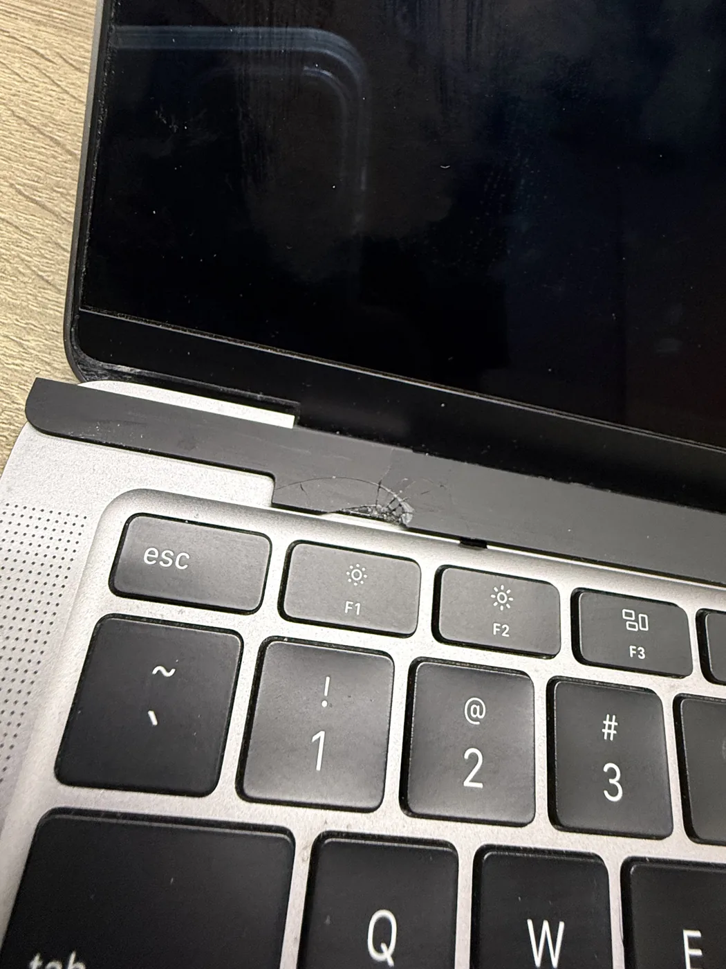 Cracked bezel on a MacBook Air screen near the hinge