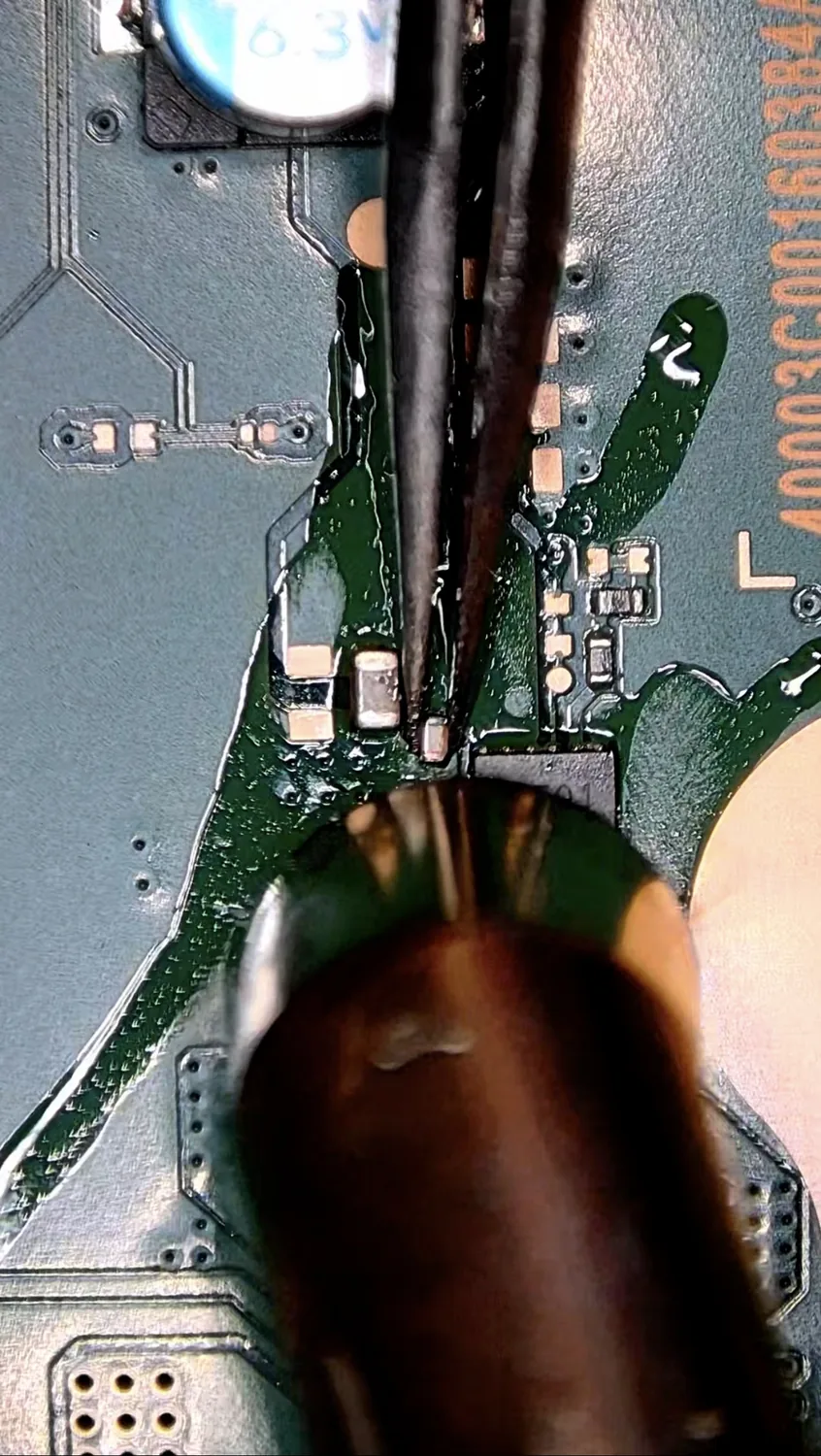 The shorted capacitor located on the PS5 logic board under the microscope with flux applied