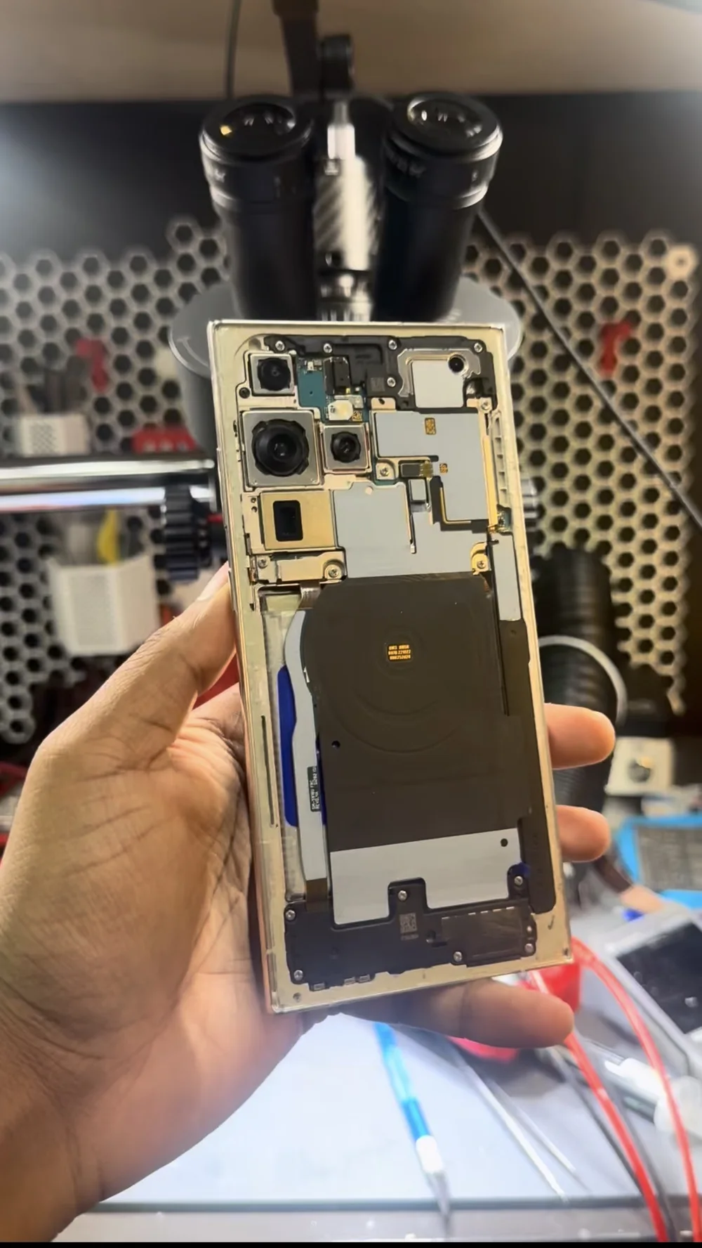 Samsung Galaxy S23 Ultra opened at the repair bench with the back cover removed, showing the cameras, wireless charging coil and board shields