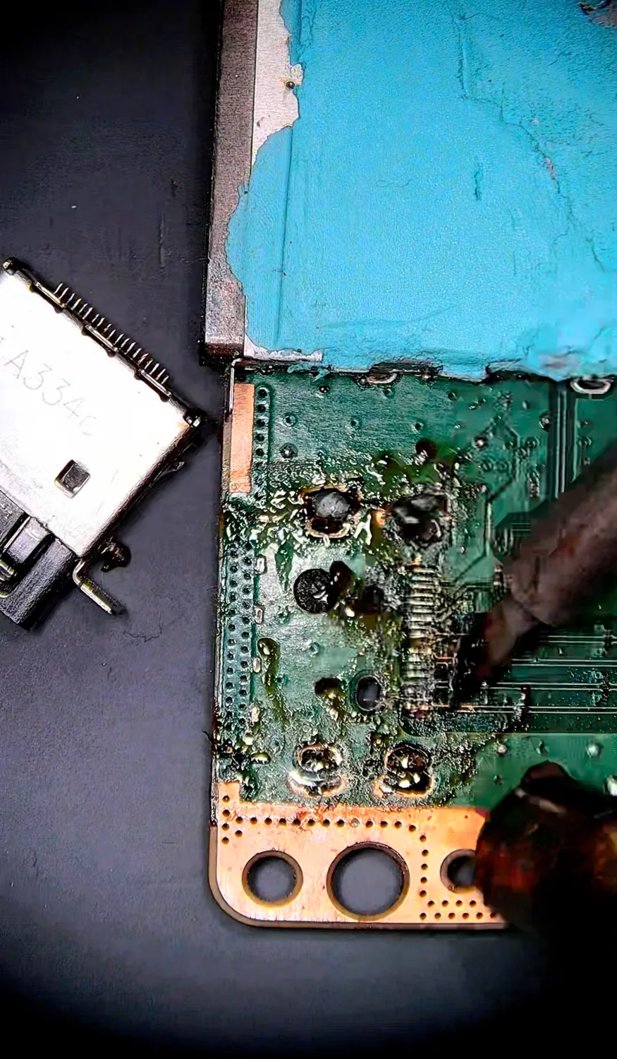 Close-up of the burnt, flux-caked Xbox HDMI footprint with two ripped pads